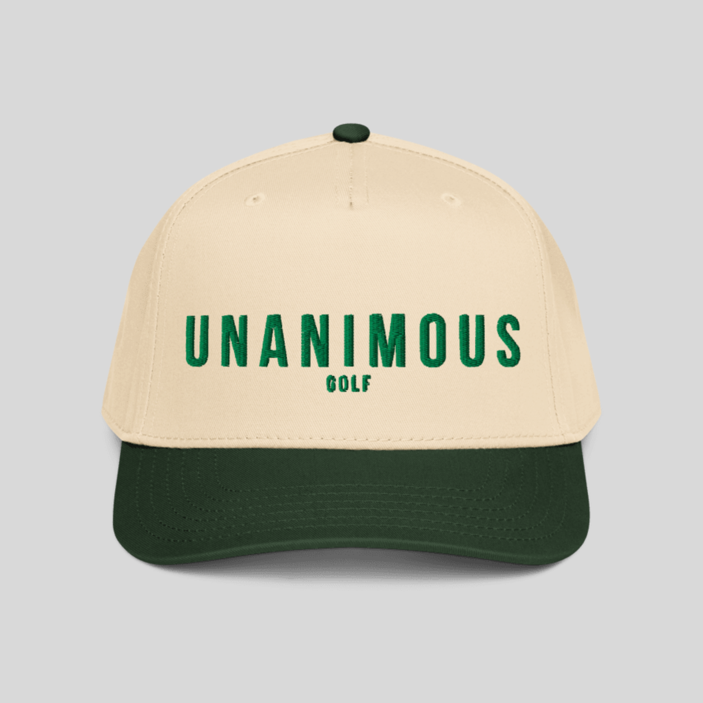 A structured baseball cap with a cream-colored crown and a dark forest green visor, featuring the text 'UNANIMOUS GOLF' embroidered in green on the front. The cap is photographed against a solid light gray background.