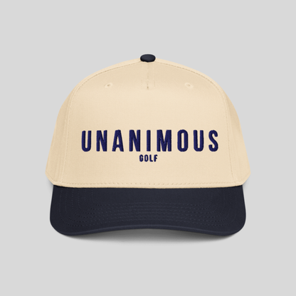 A structured baseball cap with a cream-colored crown and a dark navy blue visor, featuring the text 'UNANIMOUS GOLF' embroidered in navy blue on the front. The cap is photographed against a solid light gray background.