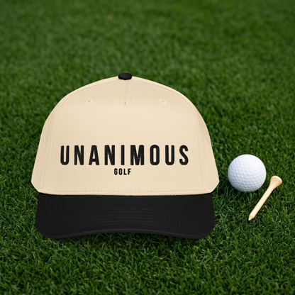A beige and black baseball cap with 'UNANIMOUS GOLF' printed on the front, displayed on a green grass surface next to a white golf ball and wooden tees.