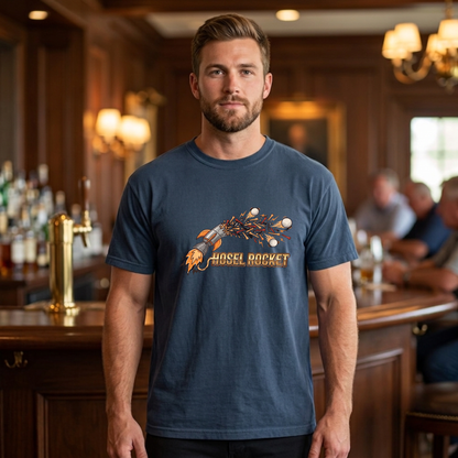 A man wearing a true navy blue crewneck t-shirt with a rocket ship graphic and the text 'NOSEL ROCKET' in a warm, wood-paneled bar environment.